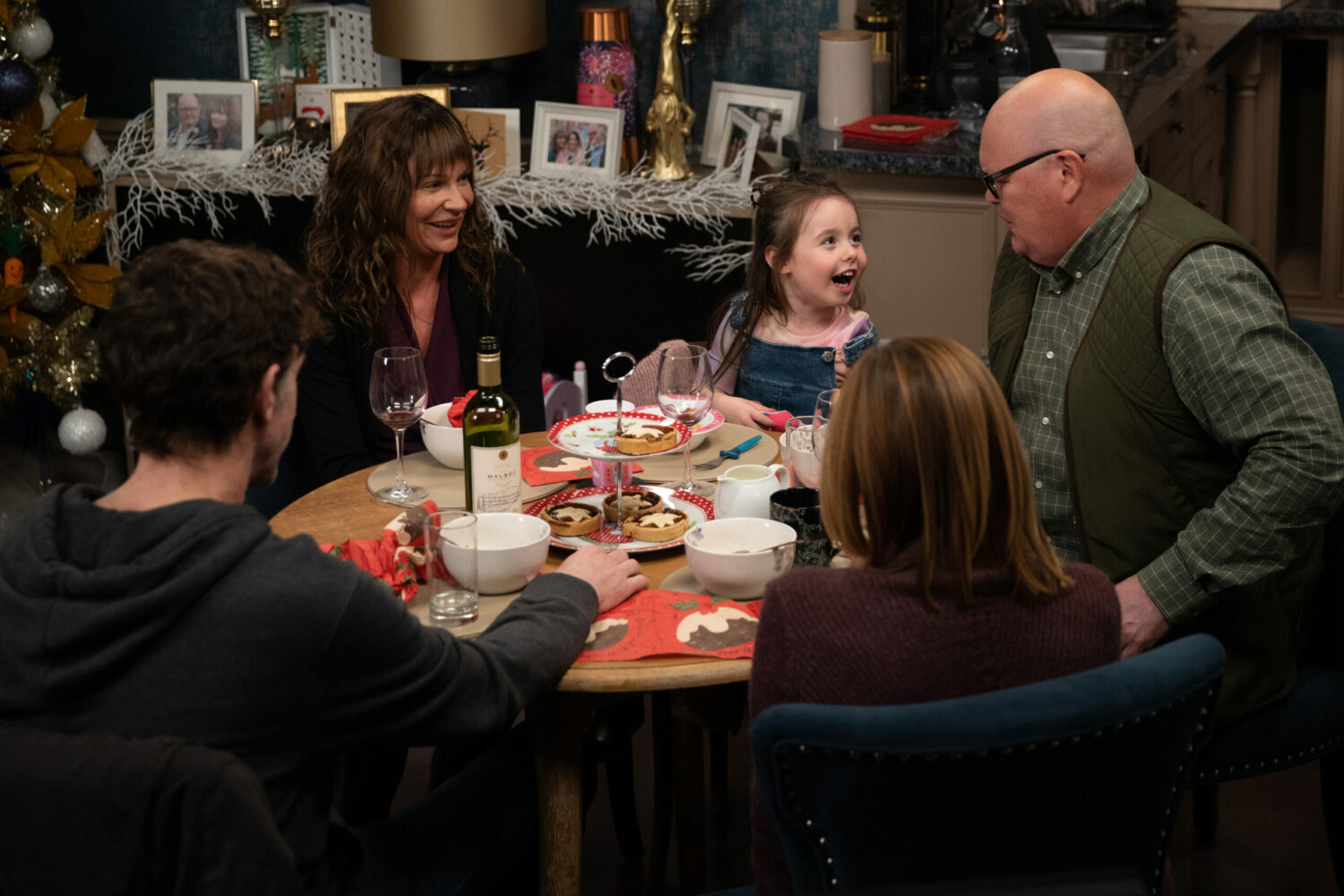 Chas, Paddy, Rhona, Marlon and Eve smile at the dinner table in Emmerdale 
