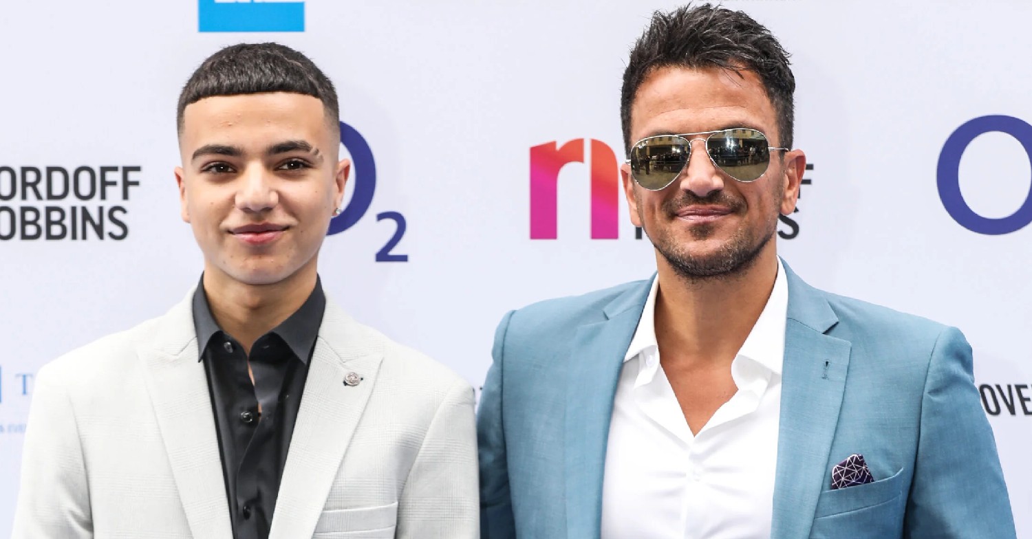 Junior Andre and Peter Andre smiling on a red carpet 