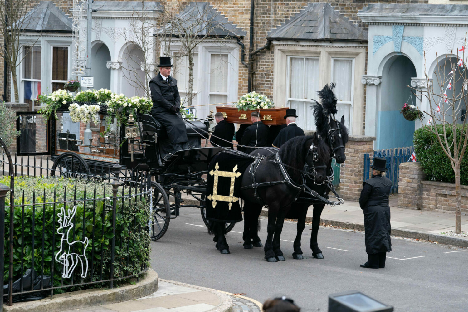 A horse drawn funeral carriage waits as Dot's coffin is loaded in