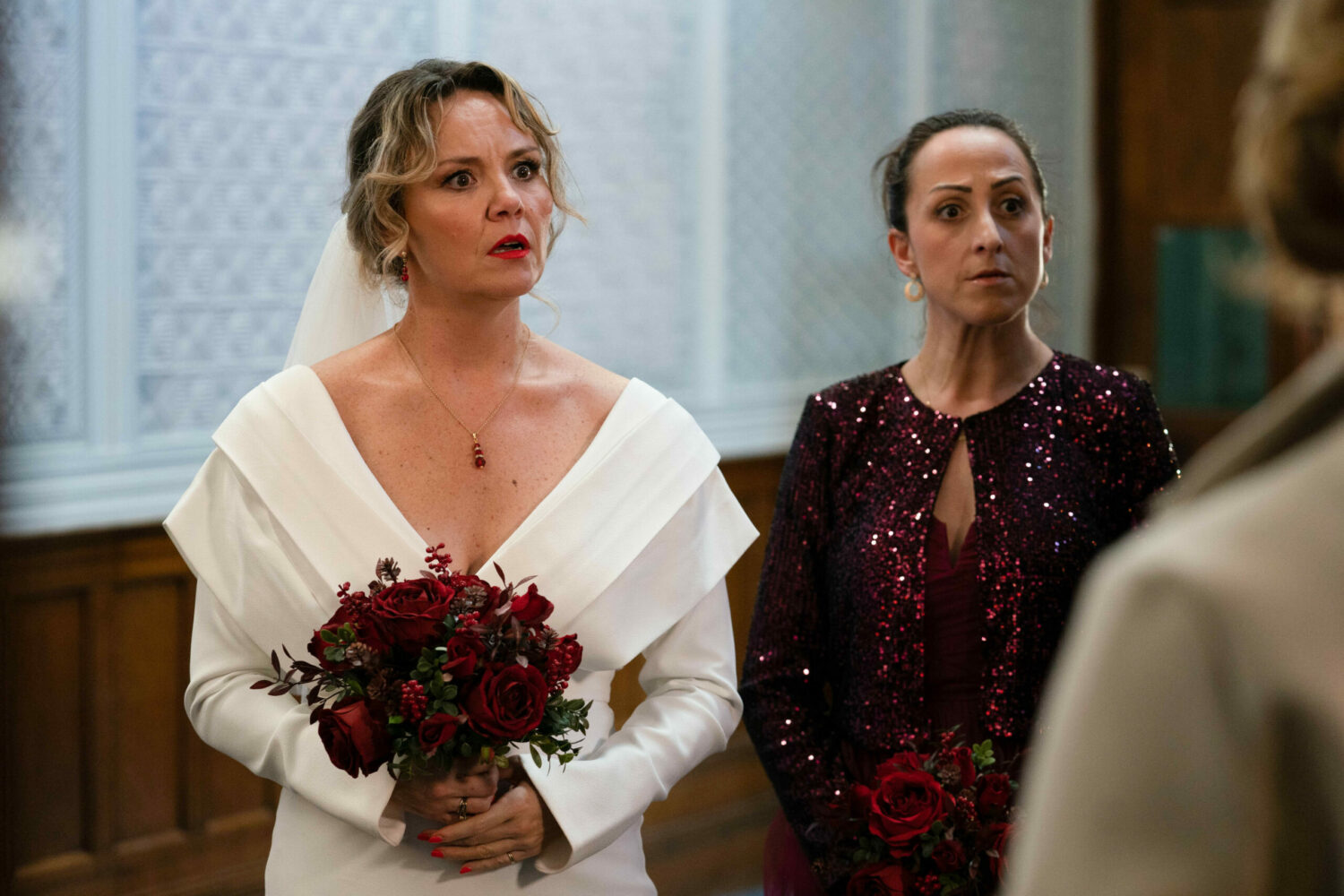 Janine Butcher and Sonia Fowler in EastEnders dressed for Janine's wedding, looking horrified