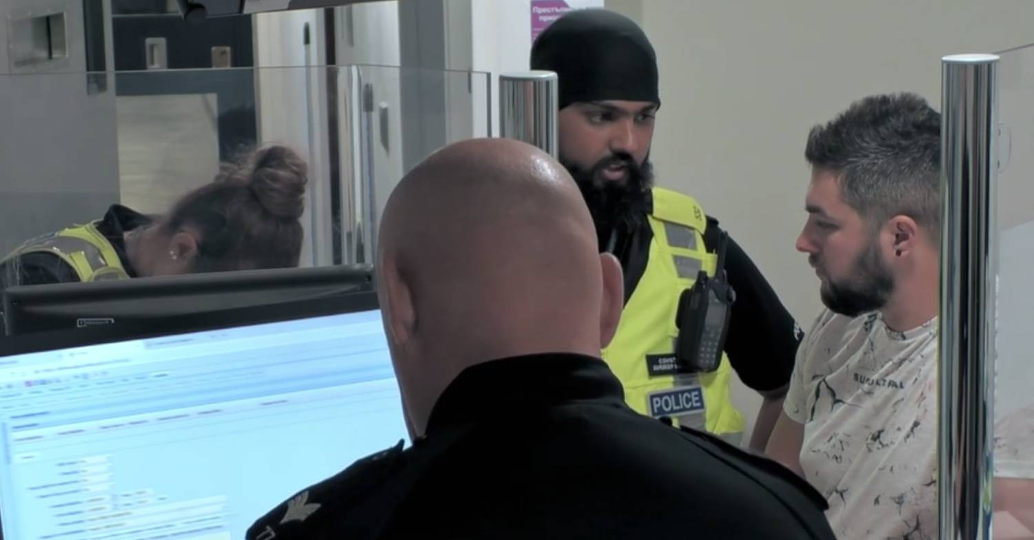 A duty sergeant interacts with Adam White at the police station during 24 Hours In Police Custody