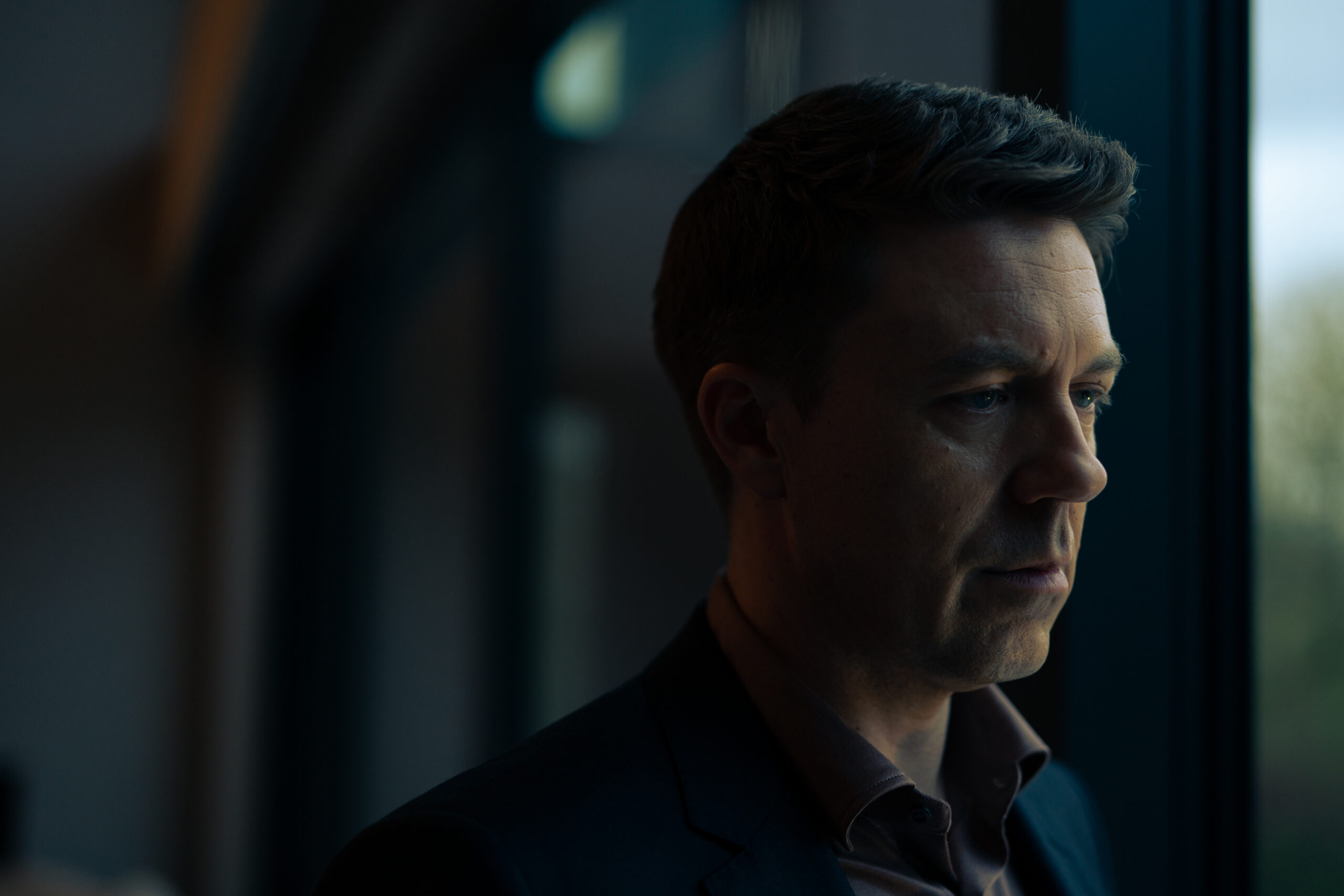 Col McHugh looks out a window in Better episodes