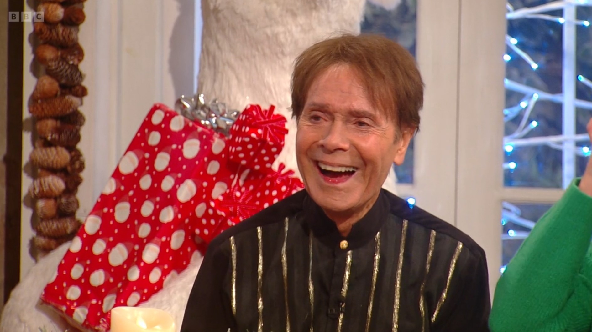 Cliff Richard laughs in a black and gold striped grandad shirt