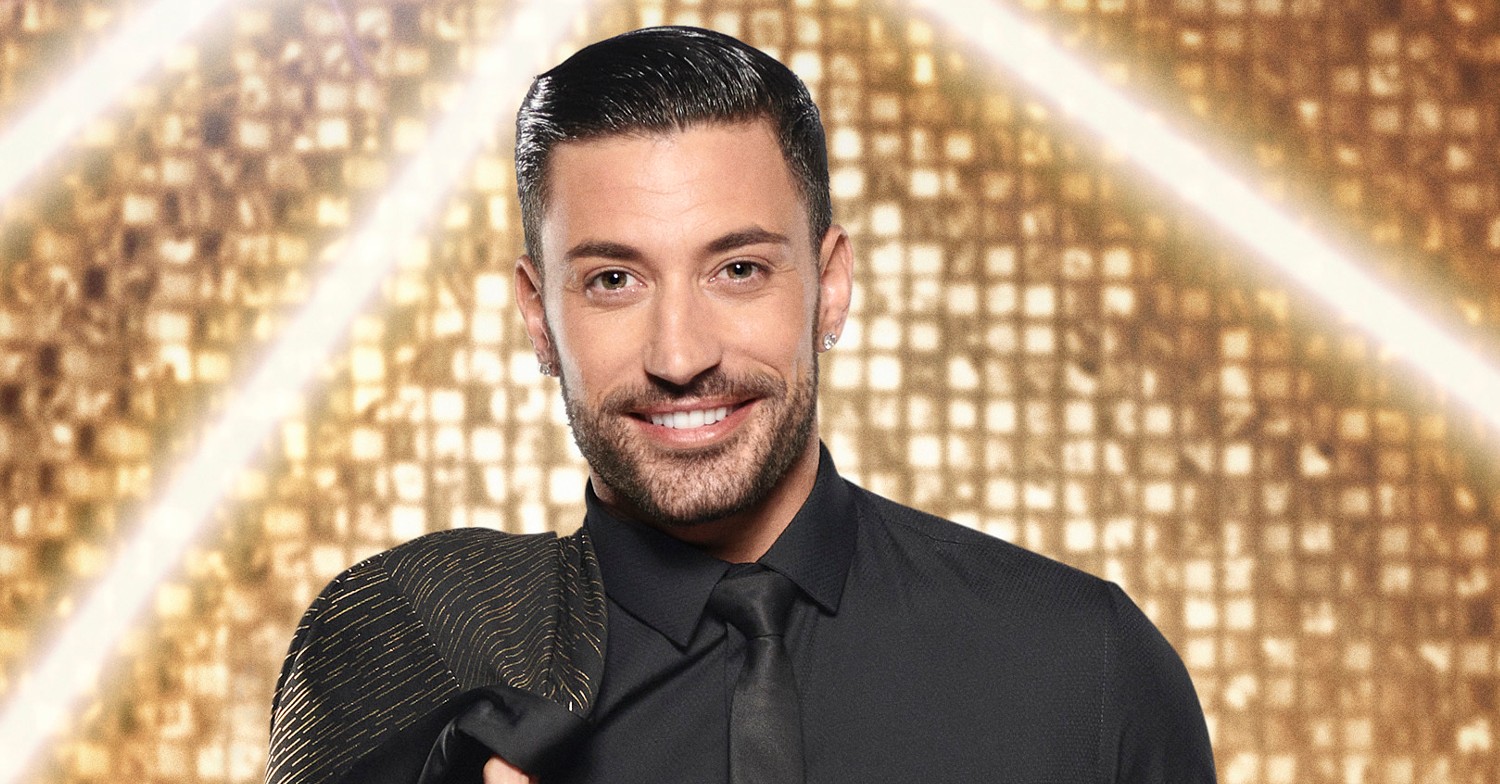 Giovanni Pernice smoulders in Strictly press shot in black suit with gold background