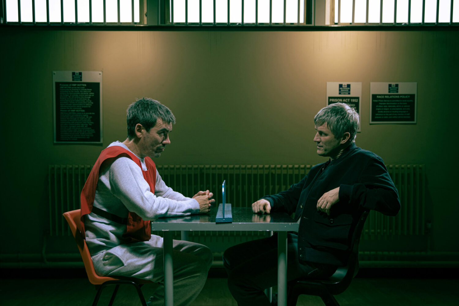 Cain and Caleb talk over the prison visiting room table in Emmerdale