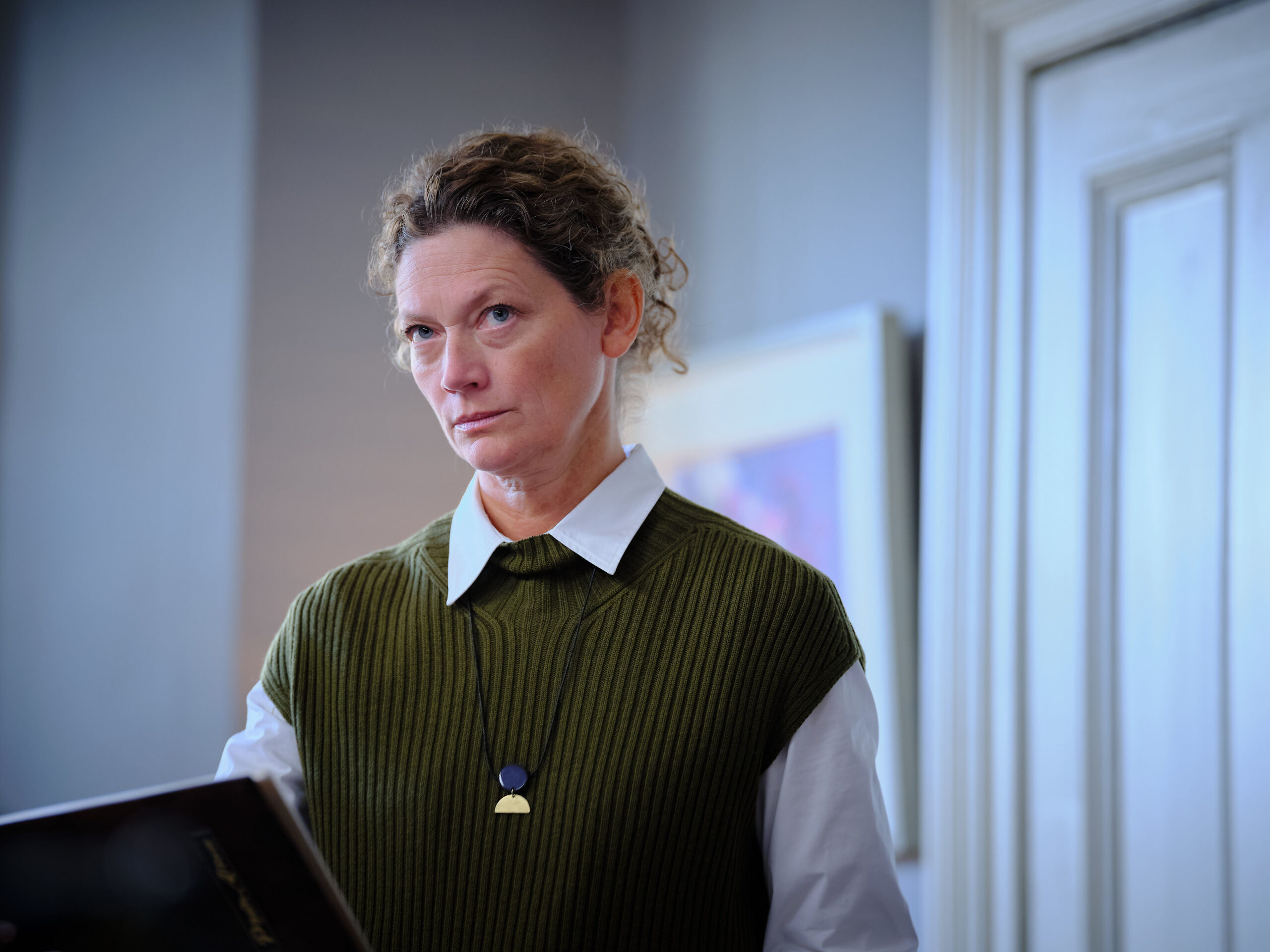 Anna Phipps stands in her home with a book
