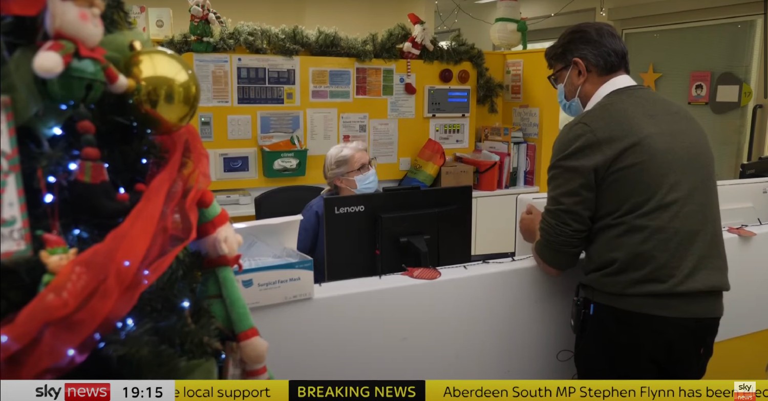 Man speaking to receptionist at doctor's surgery 