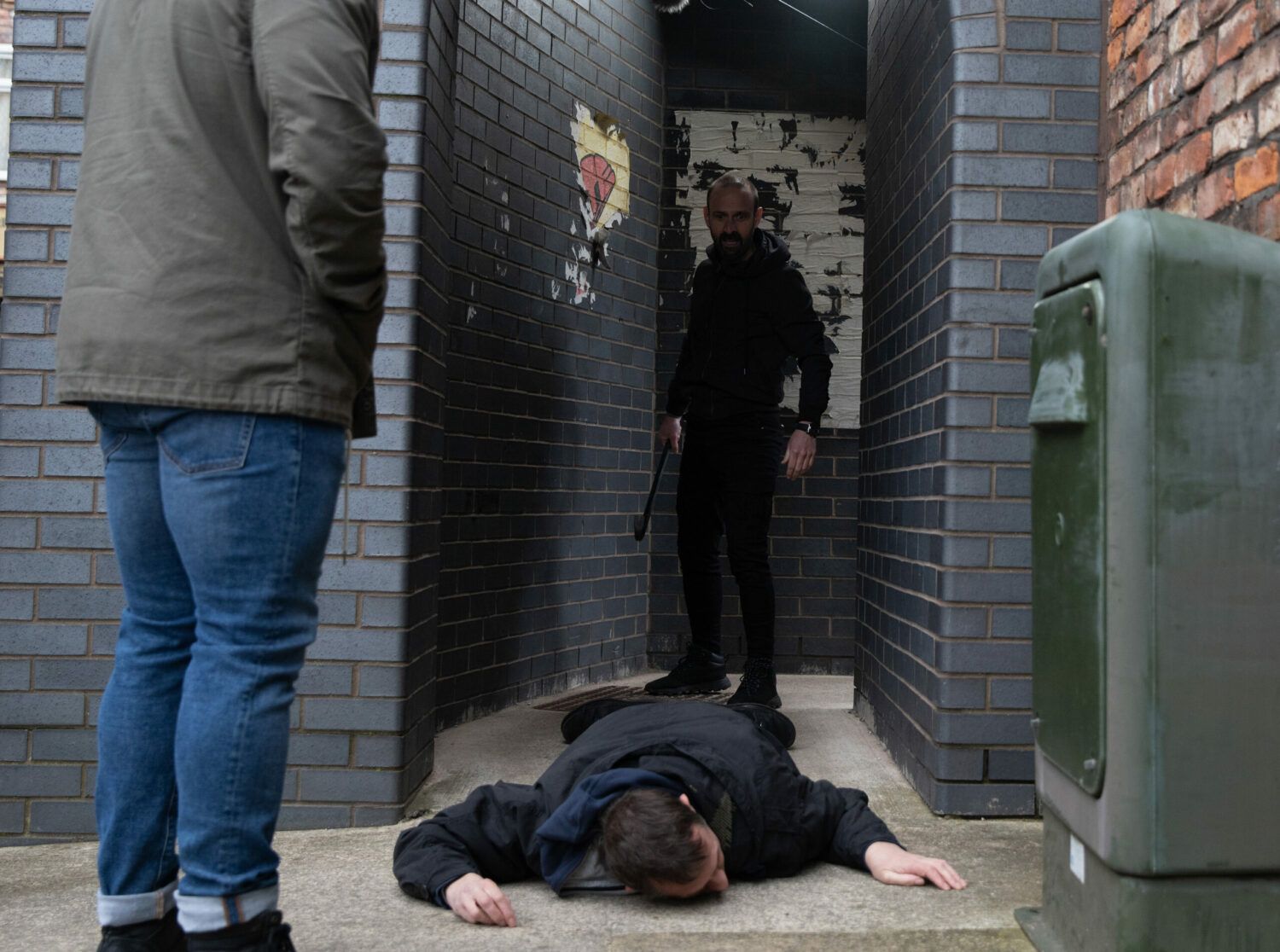 Griff stands over an unconscious Spider, holding a crowbar on Corrie