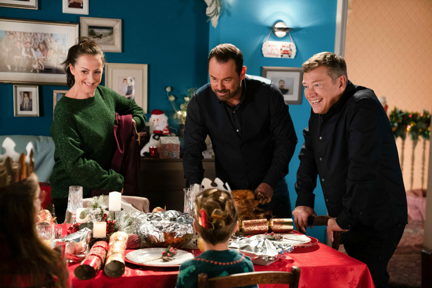 Sonia, Mick and Ricky smile as they look at the table in EastEnders