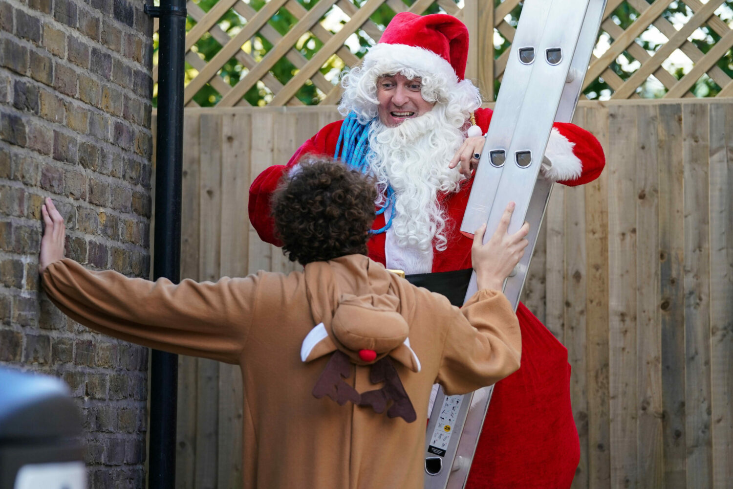 Alfie Moon dressed as Santa prepares to climb a ladder