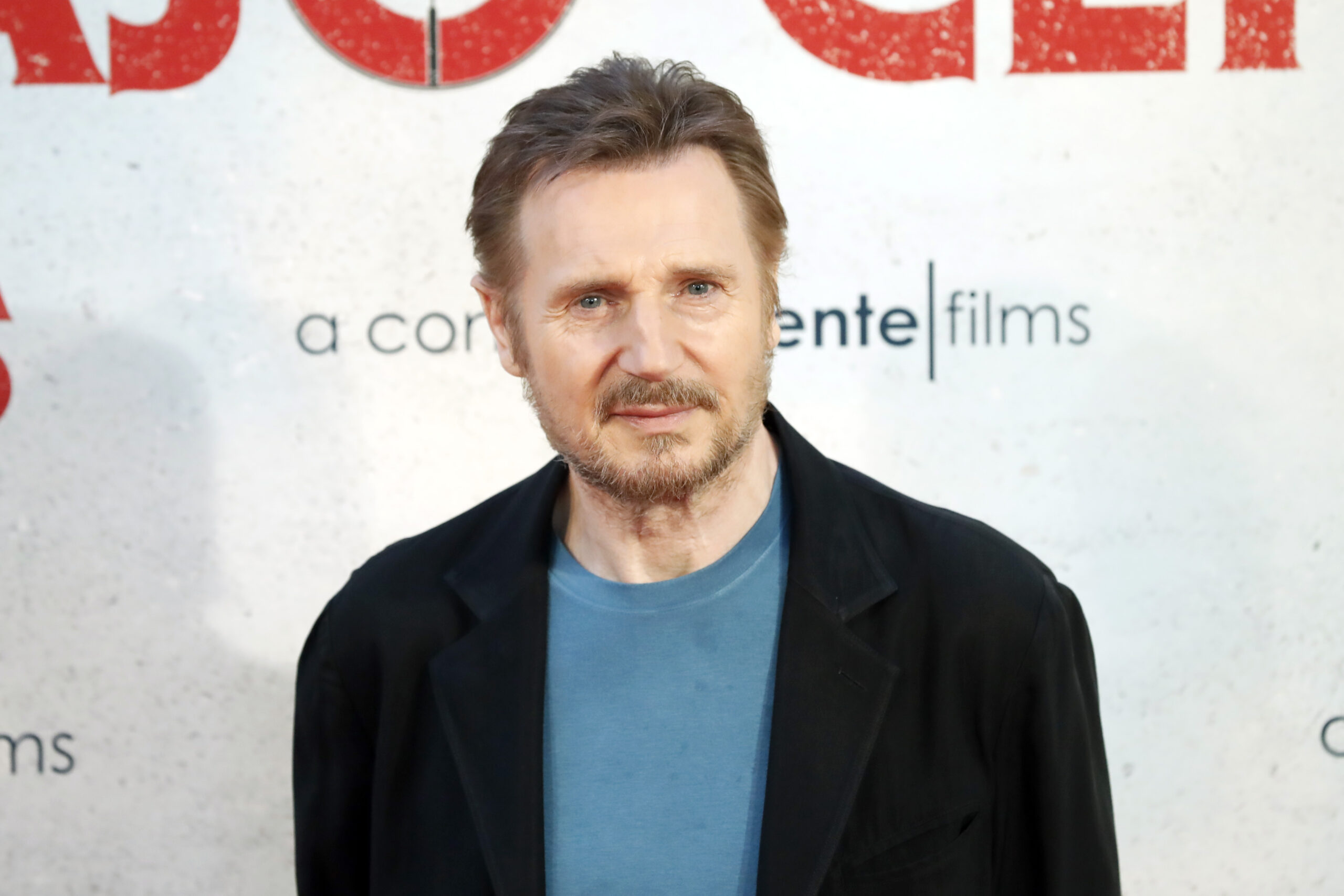 Liam Neeson at a film premiere in a T-shirt and jacket