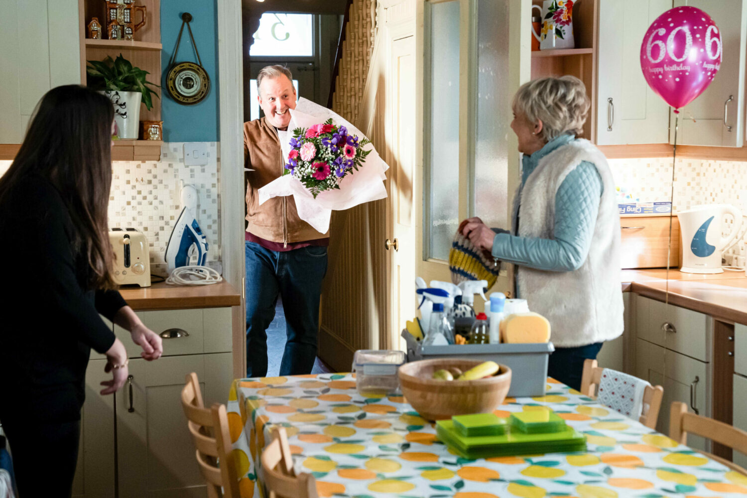 EastEnders' Harvey is holding a bouquet of flowers as he looks at Jean and Stacey