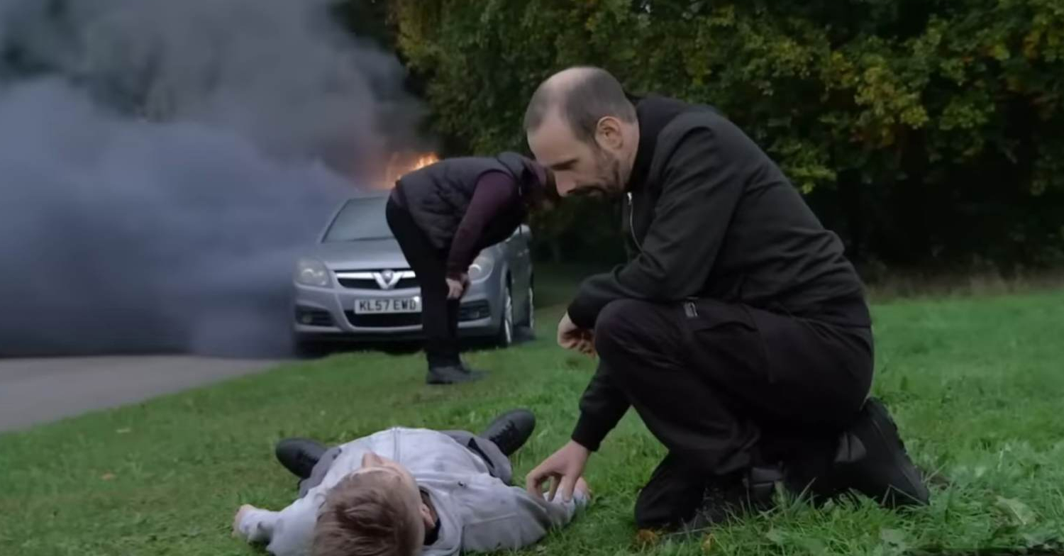 Coronation Street's Griff is tending to Max, with an exploded car in the background