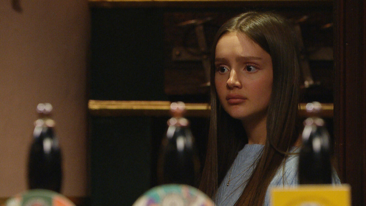 Emmerdale's Sarah is looking shocked behind The Woolpack bar