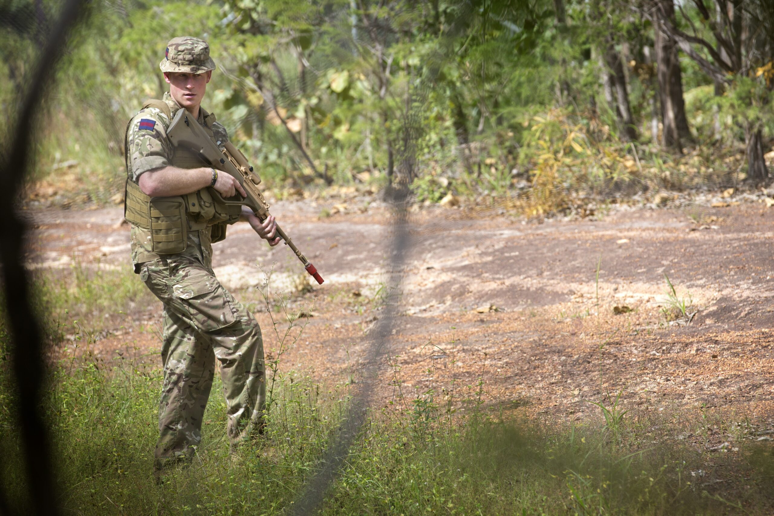 Prince Harry in Army fatigues holding a gun