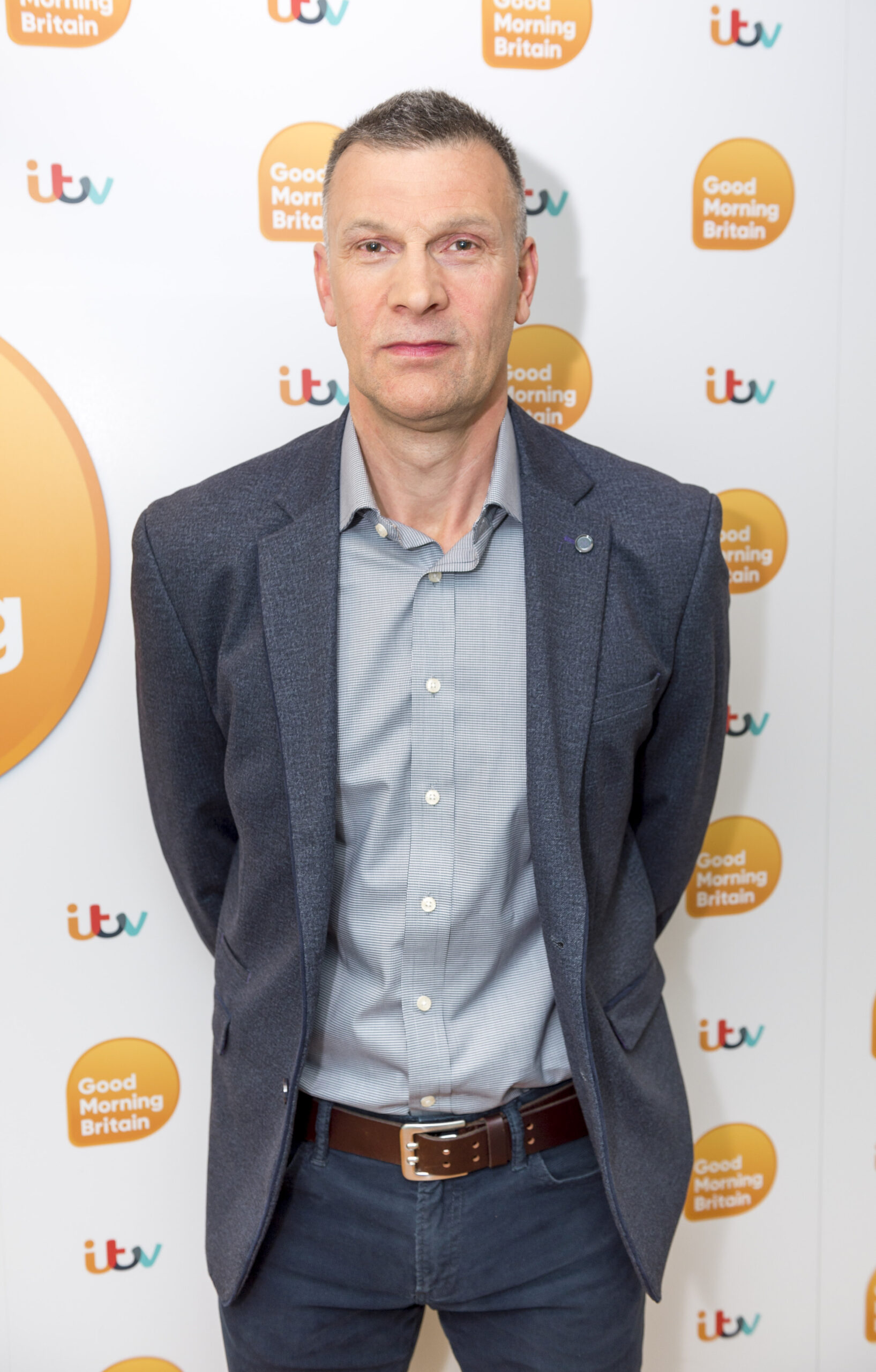 Dr Graham Hill stands in front of ITV logo