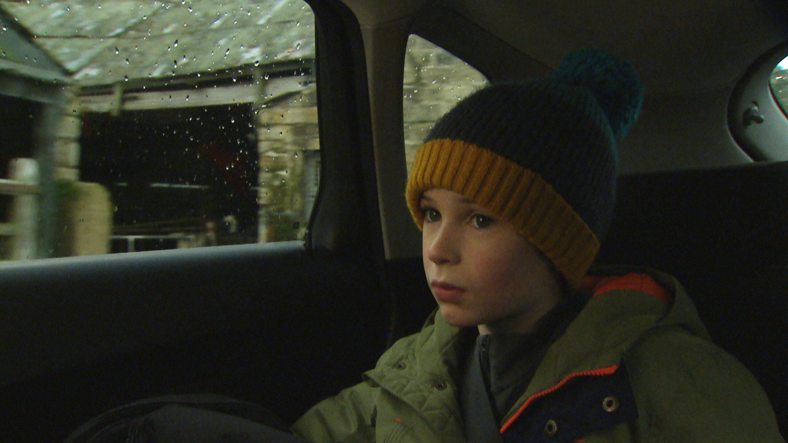 Kyle in Emmerdale sits in the back of the car looking sad