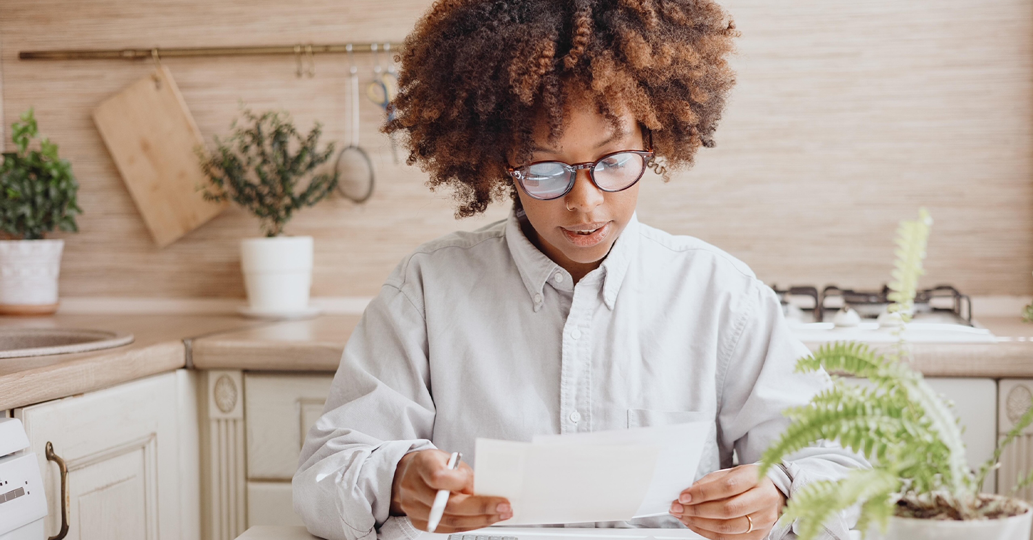 Cost of living crisis: Woman looking at her bills wearing glasses
