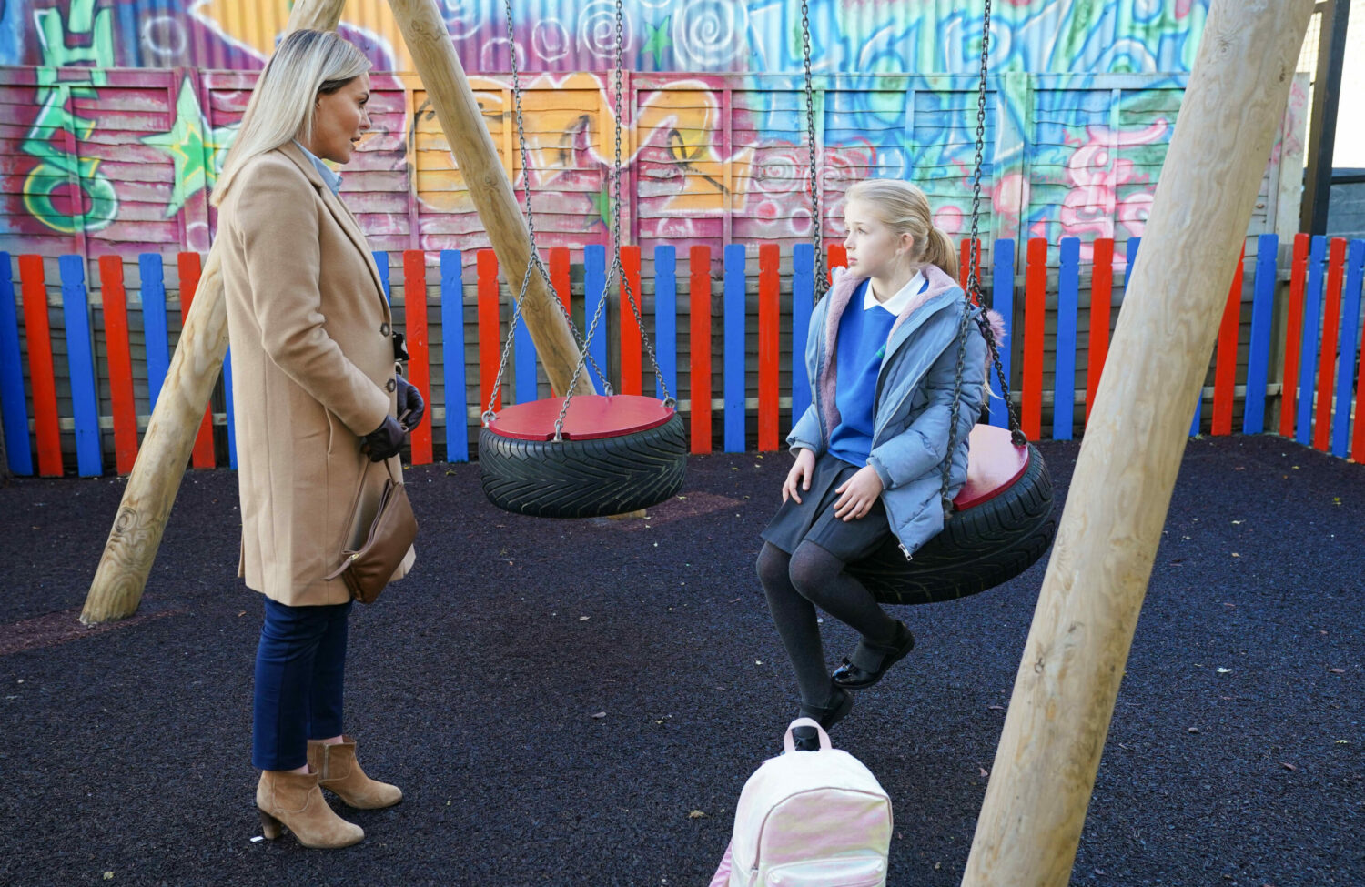 Emma talking to a sad Lexi on the swings in EastEnders