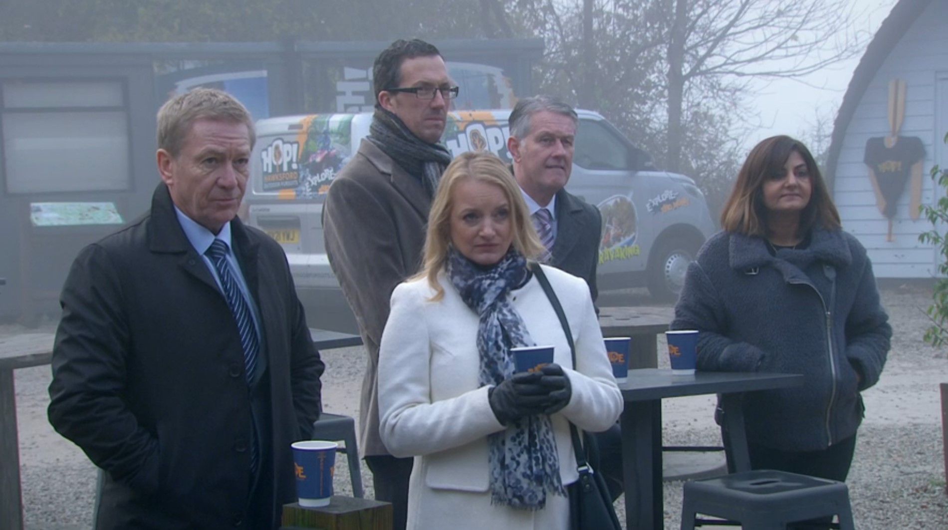 Nicola King in Emmerdale stands with the local councillors and listens to Gabby's presentation