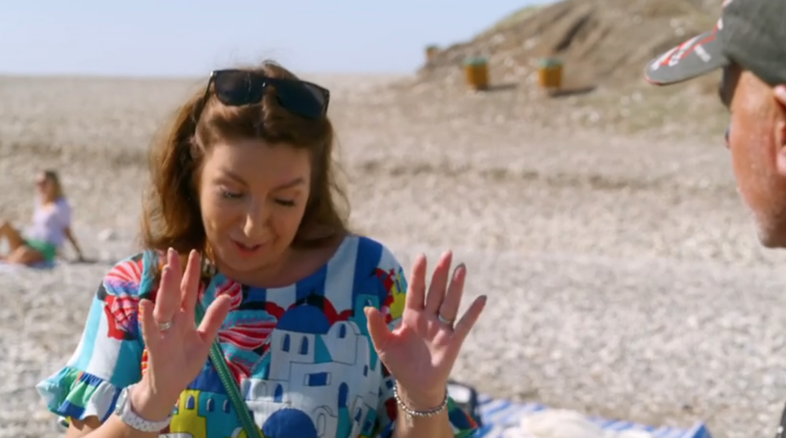 Jane McDonald holds her hands up on the beach