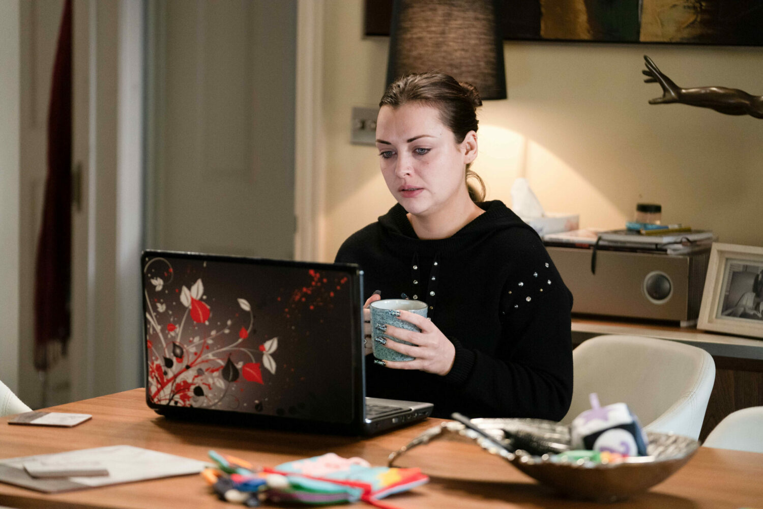 Whitney looking worried as she uses a computer on EastEnders
