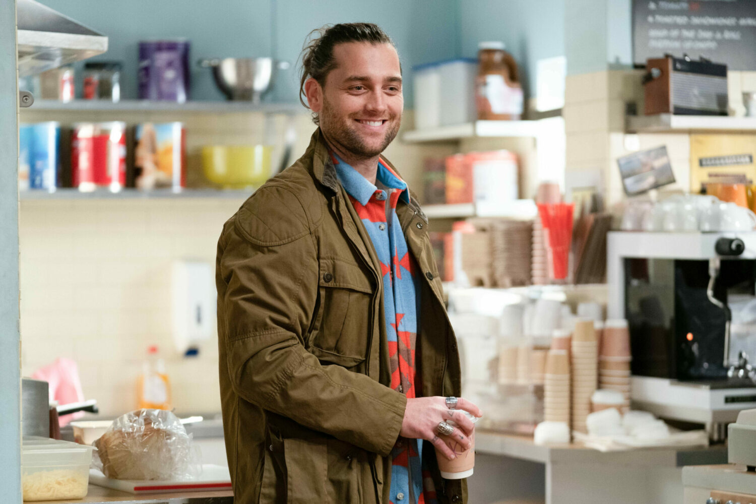 Jed grins in the cafe as he clutches a coffee in EastEnders