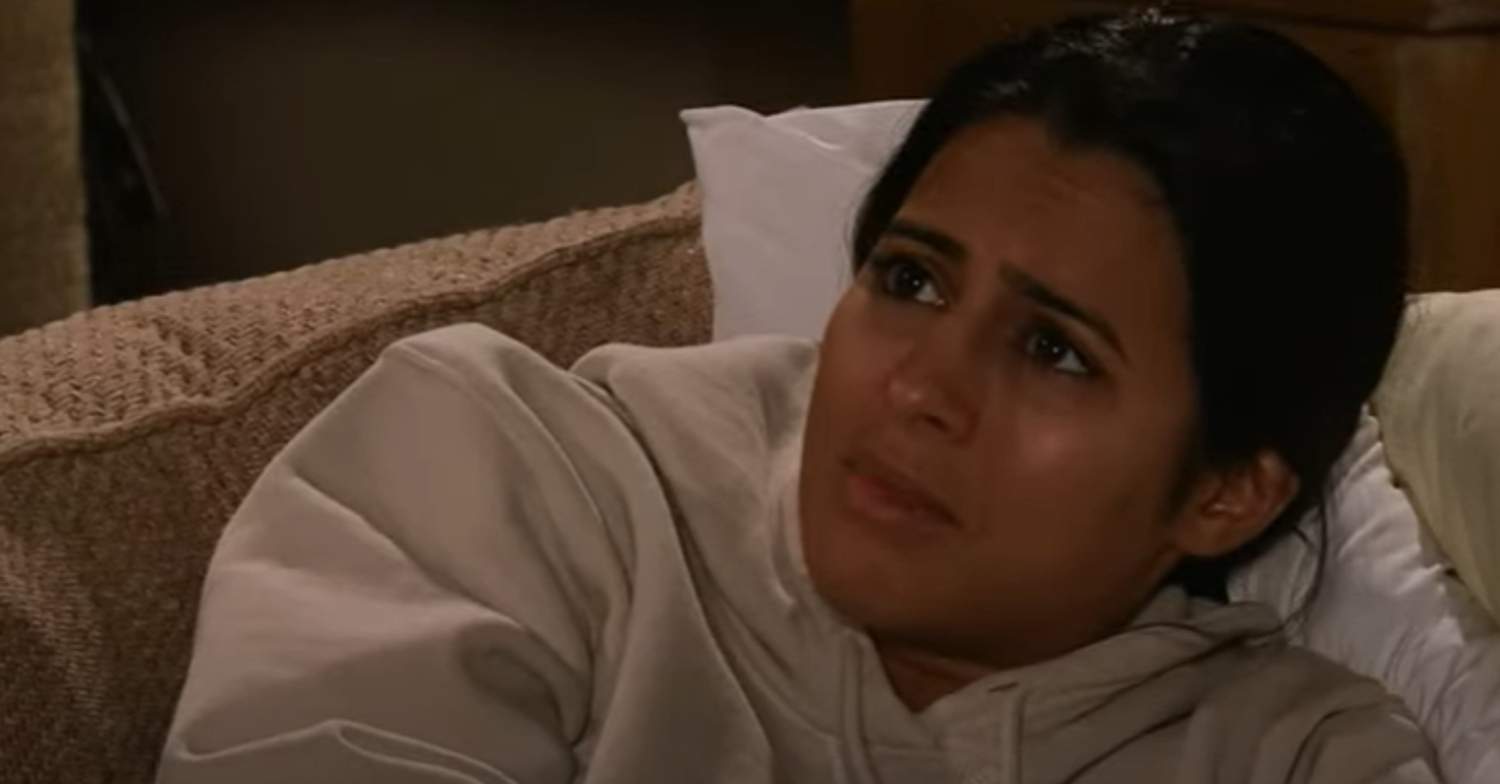 Coronation Street's Alya is looking concerned whist lying down on the sofa at home