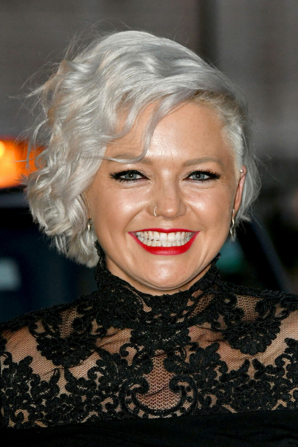 Hannah Spearritt smiles in black dress and red lipstick