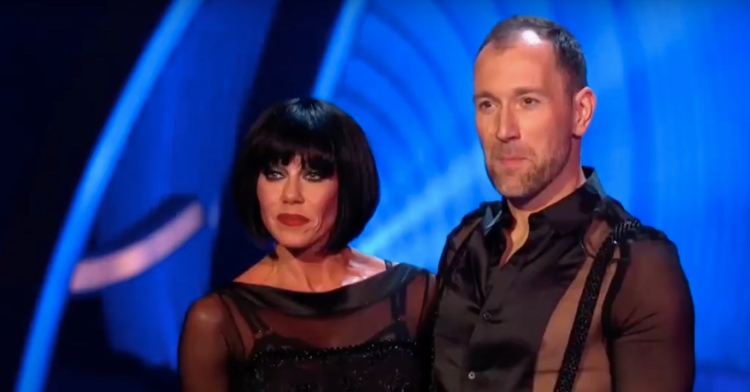 Michelle Heaton wearing a black wig and Lukasz Rozycki smiling on Dancing On Ice