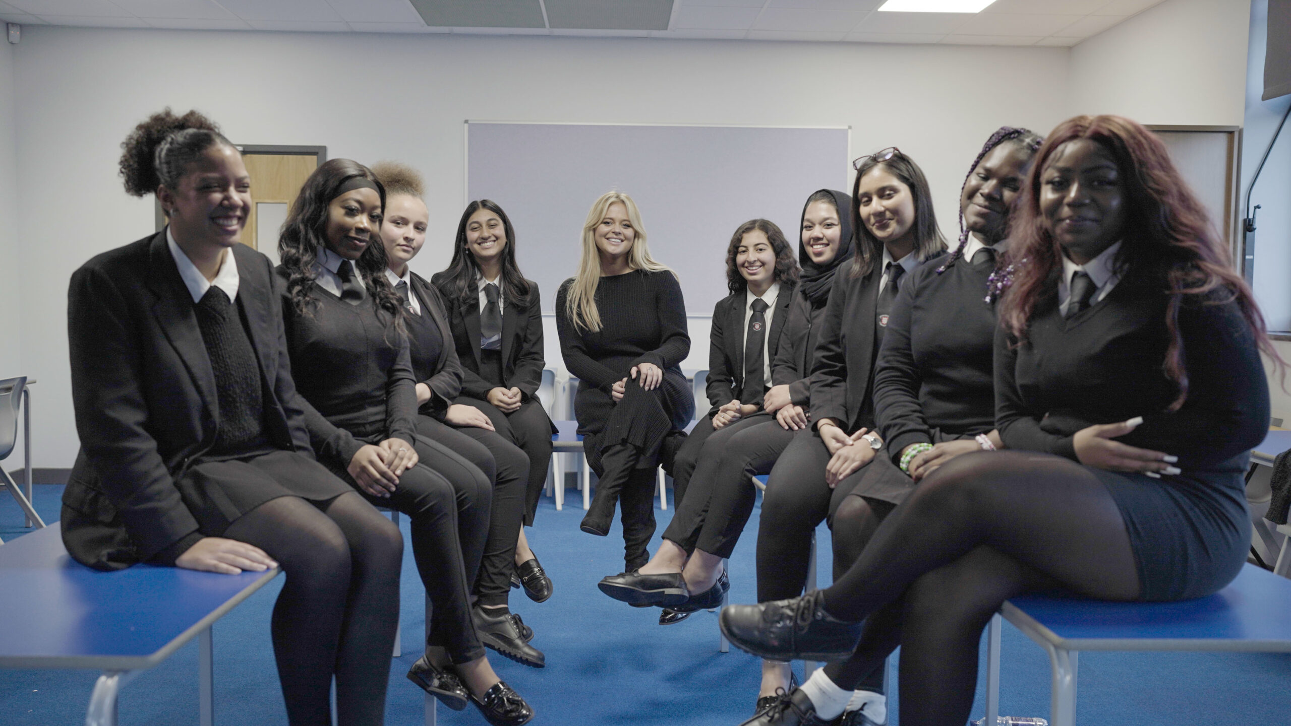 Emily Atack smiles with schoolgirls