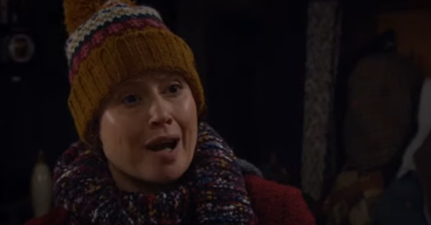 Emmerdale's Lydia is looking animated whilst wearing a woolly hat and scarf