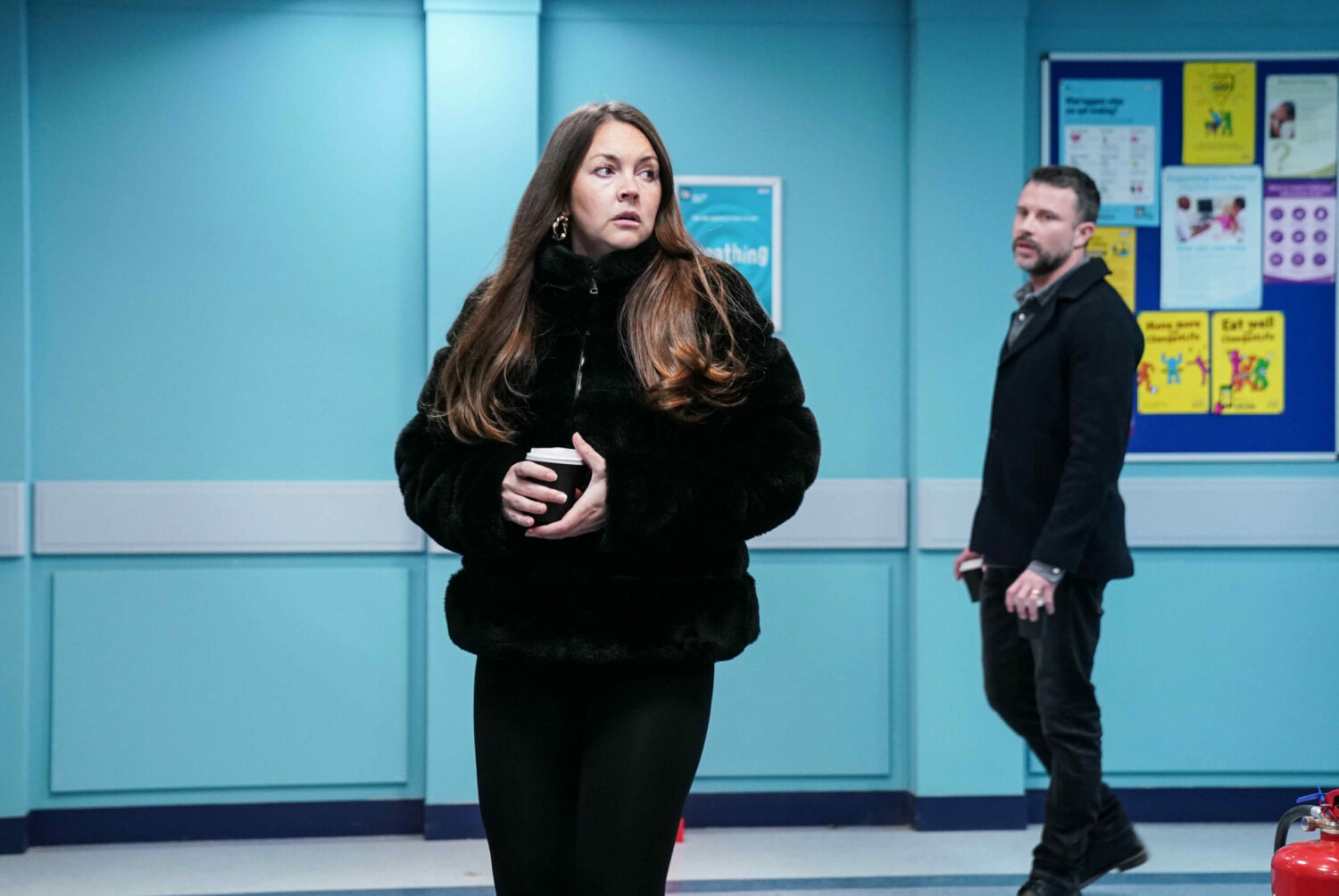 Stacey looks worried in a hospital corridor on EastEnders - behind her, Ryan approaches (Credit: BBC)