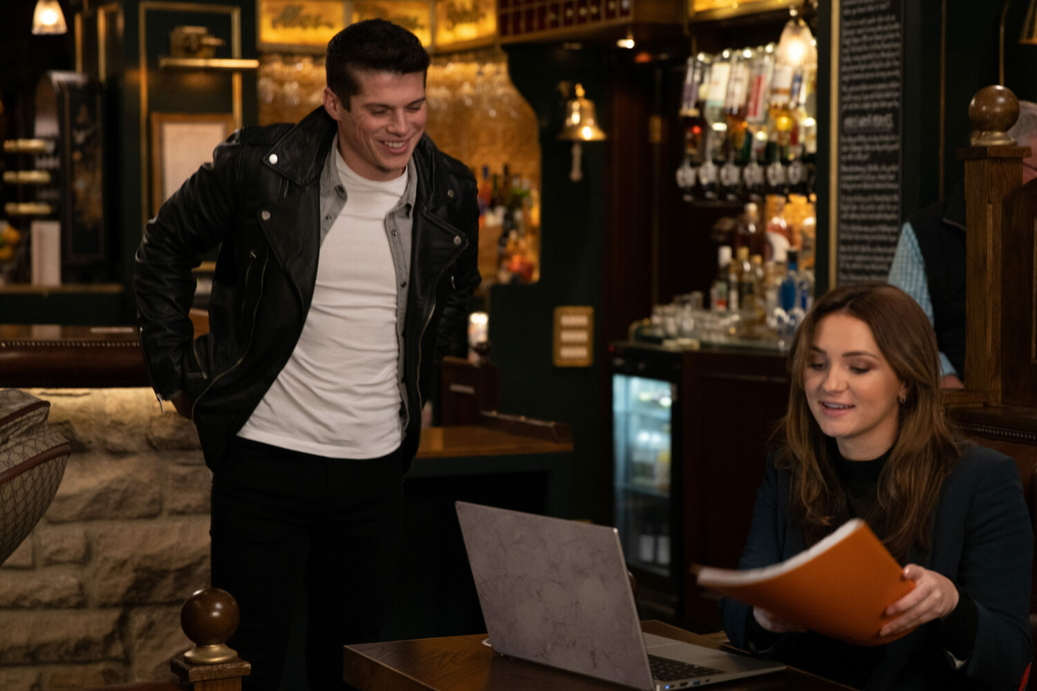 Nicky smiles at Gabby as she looks at paperwork in the Woolpack in Emmerdale