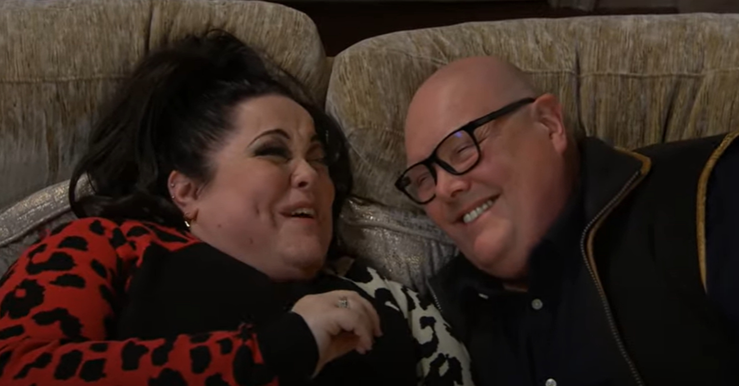 Emmerdale's Mandy and Paddy are laughing with each other on the sofa
