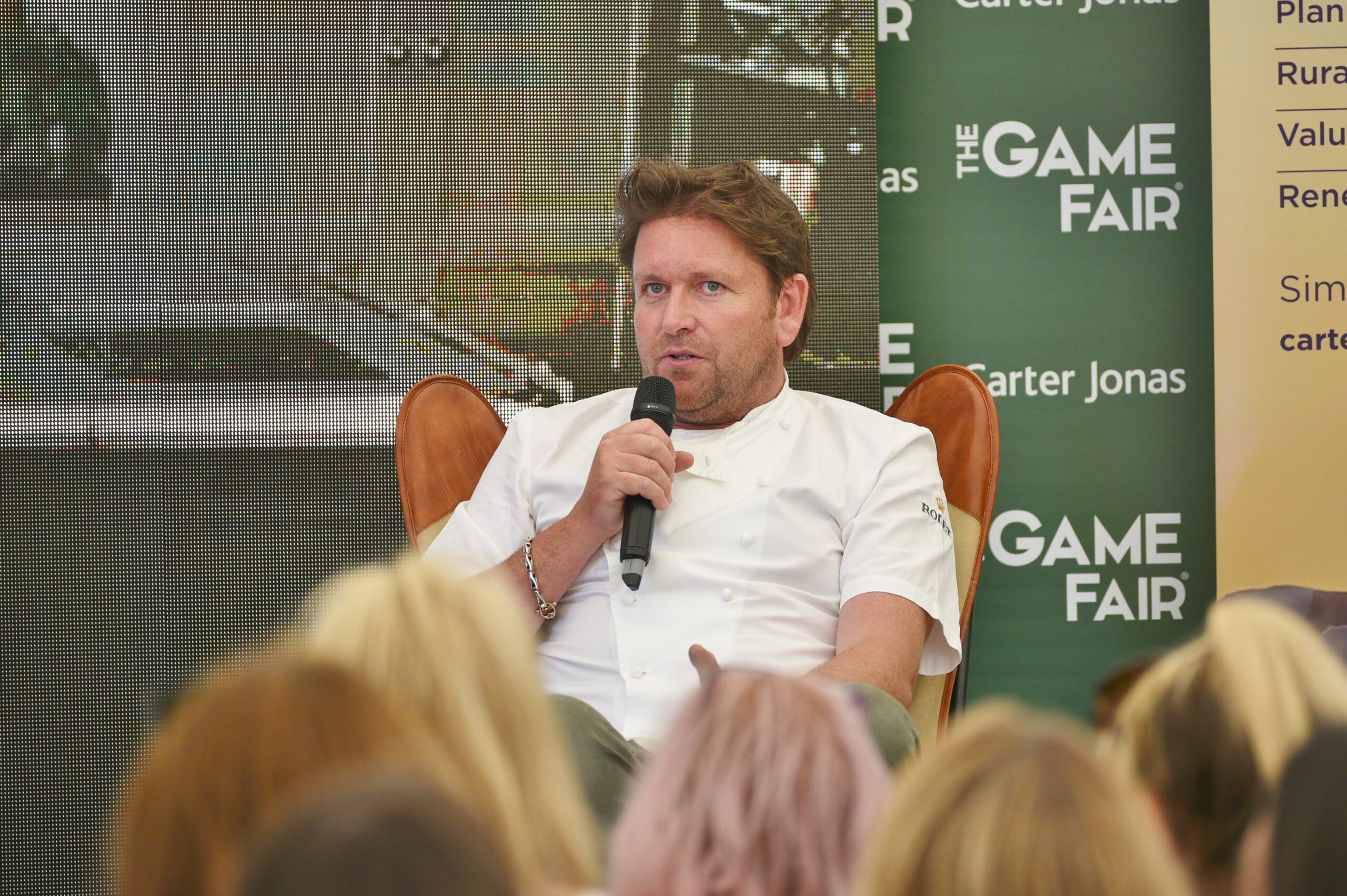 James Martin speaking into a mic on stage
