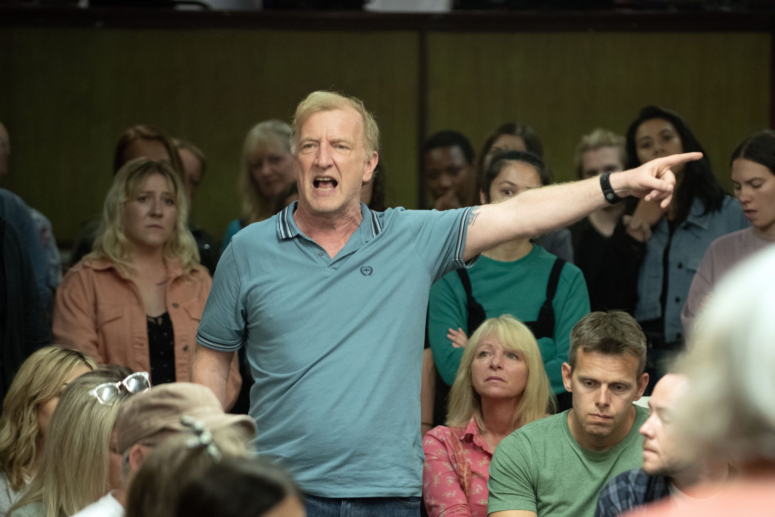 Steffan Rhodri, as Geoff in the Michael Sheen directed drama The Way, stands up and shouts in a crowd of people