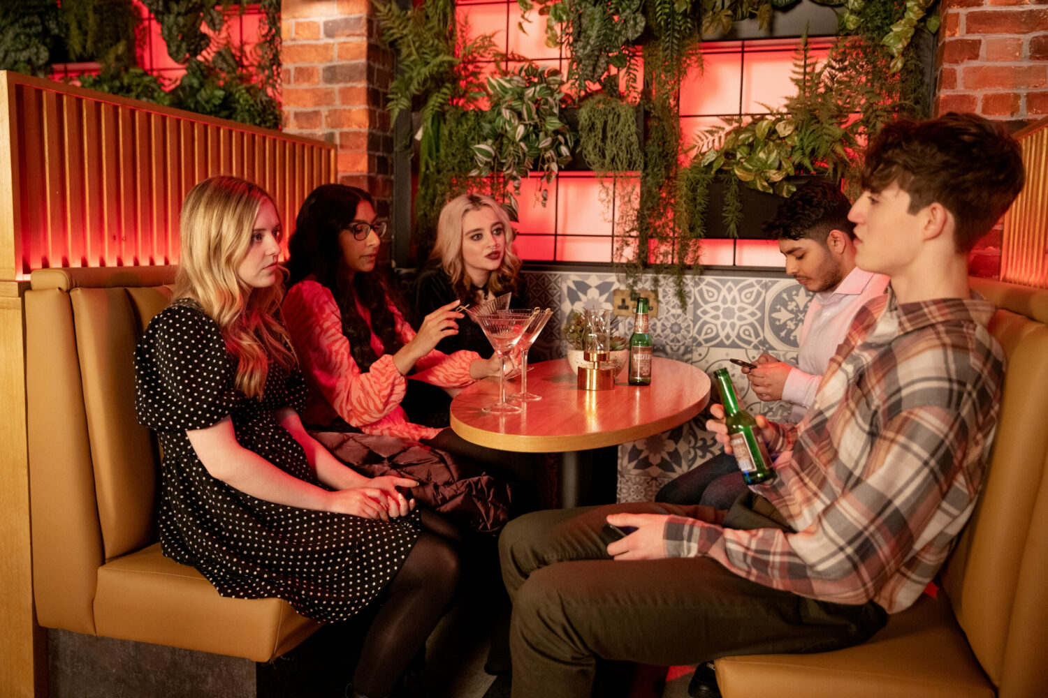 Summer, Asha, Nina, Aadi and Aaron sit round a table on a night out in Coronation Street