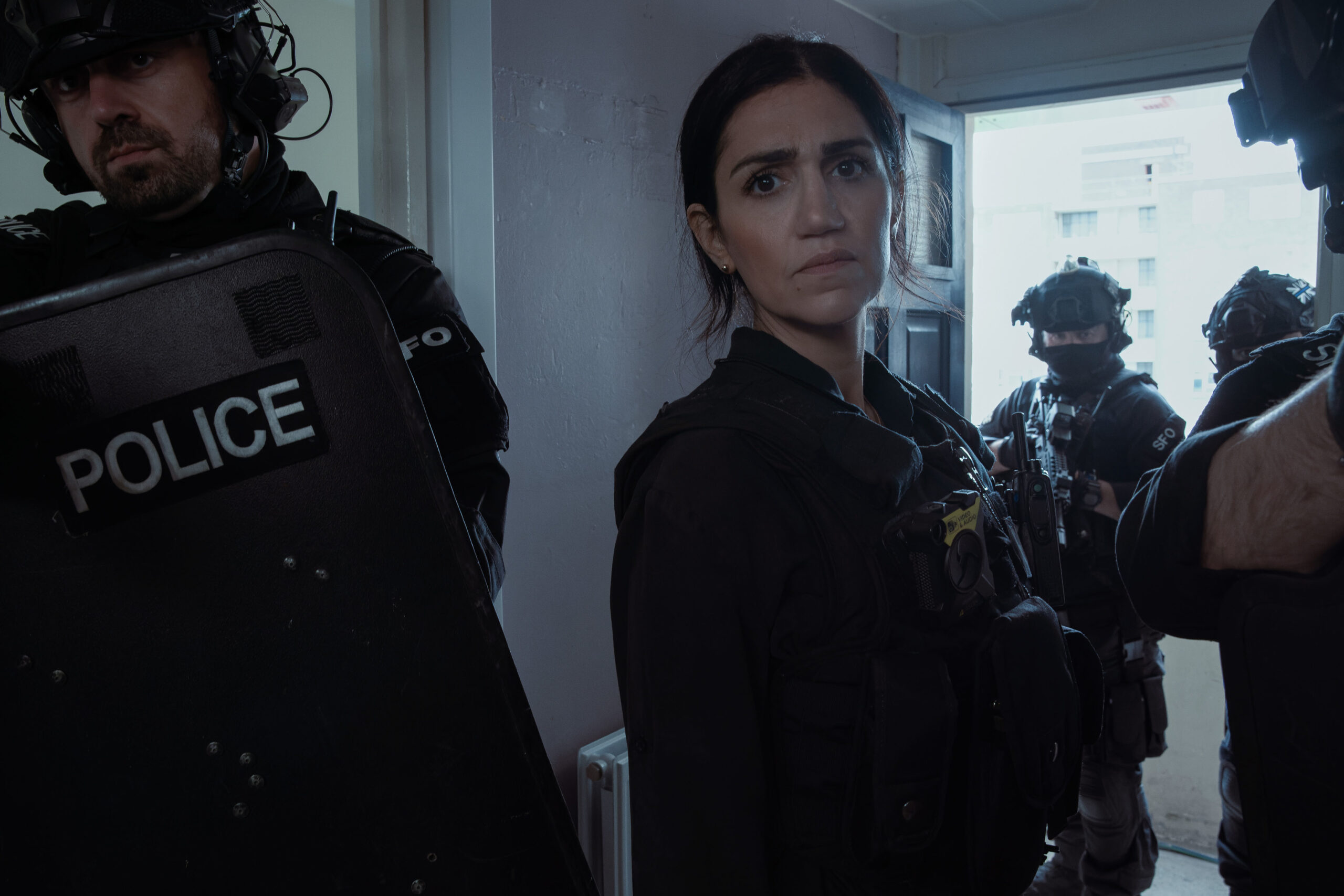 Lou Slack frowns next to armed police in Better