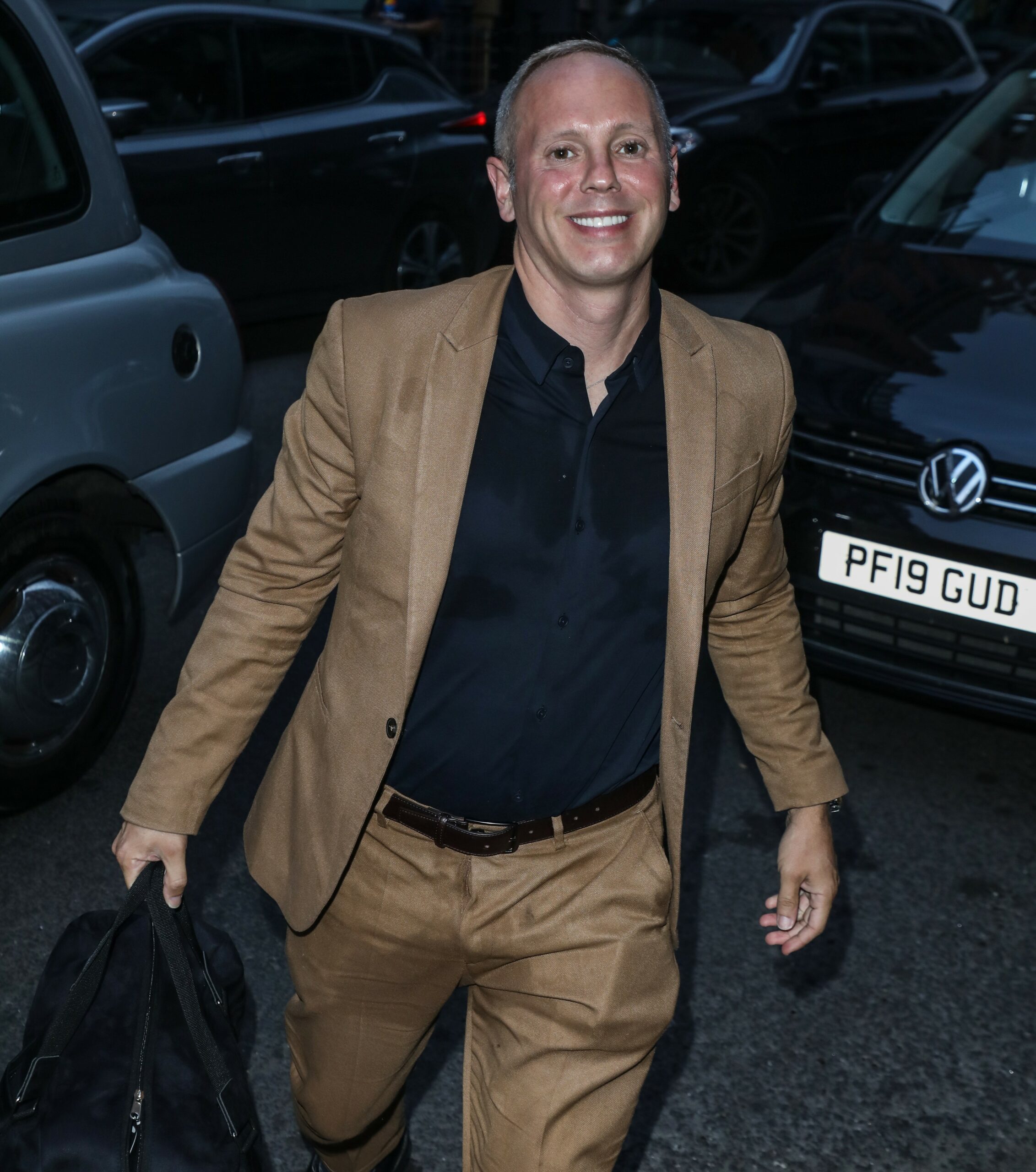 Robert Rinder smiling in brown suit