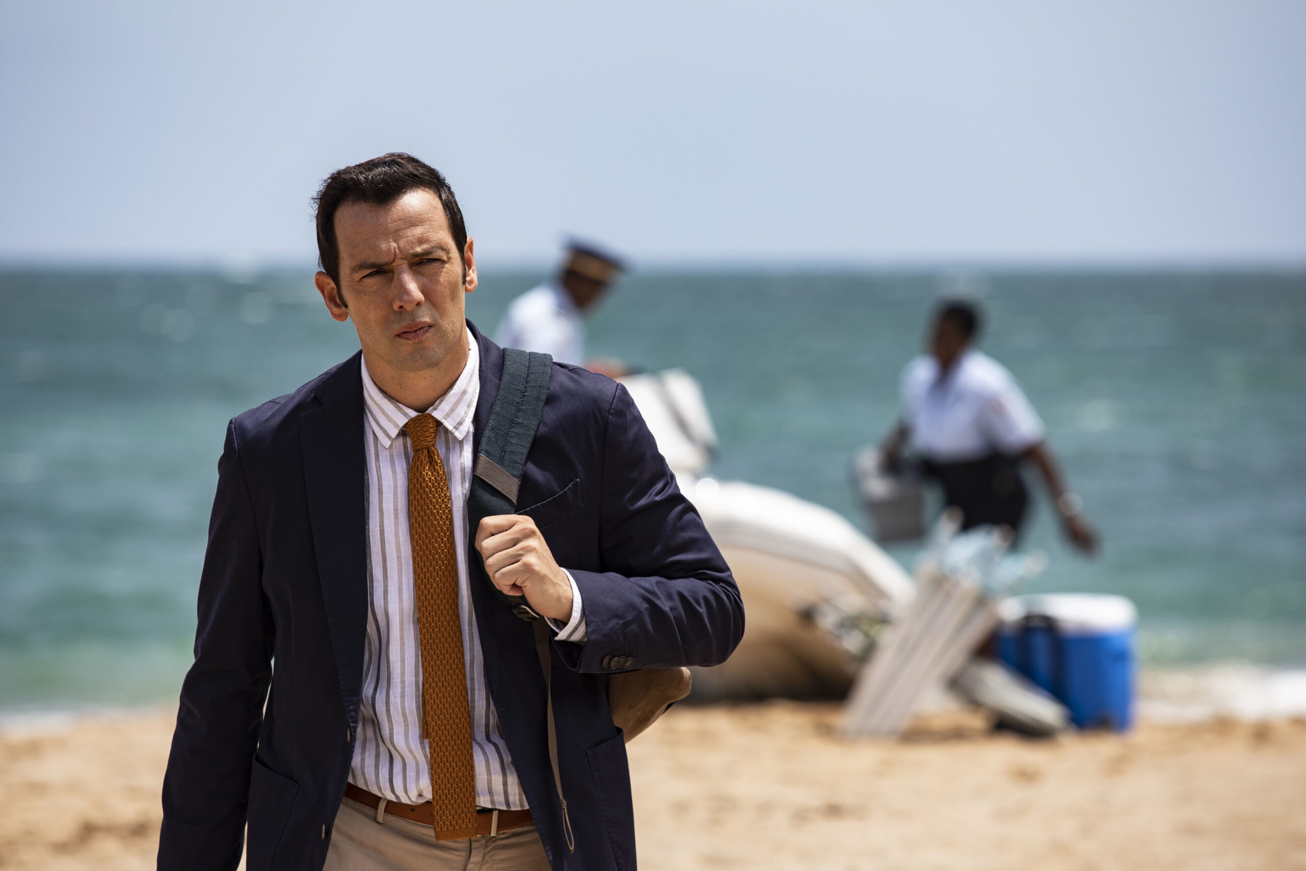 Neville Parker walks on the beach in Death in Paradise