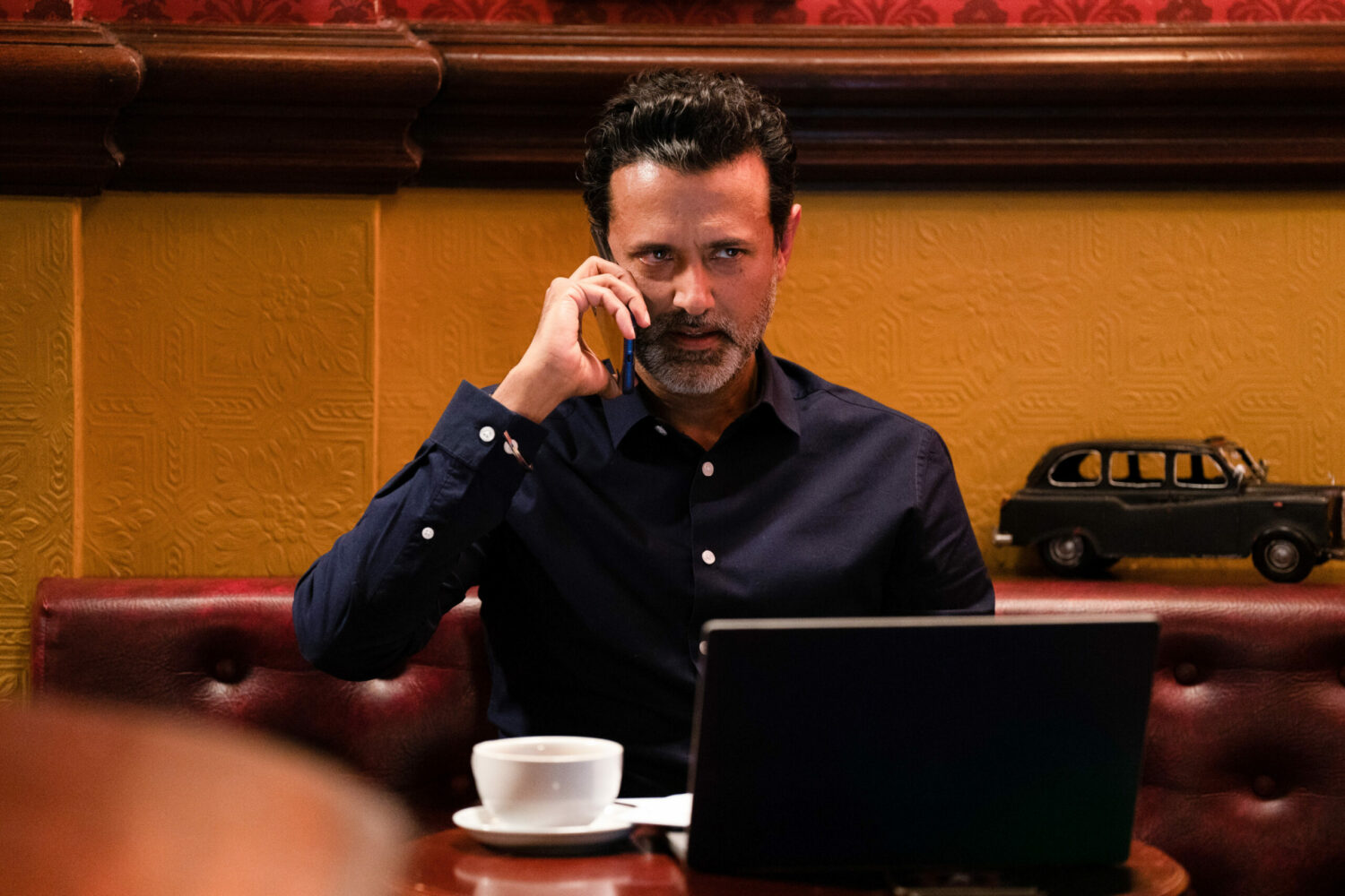 Nish looks sinister as he talks on the phone in EastEnders