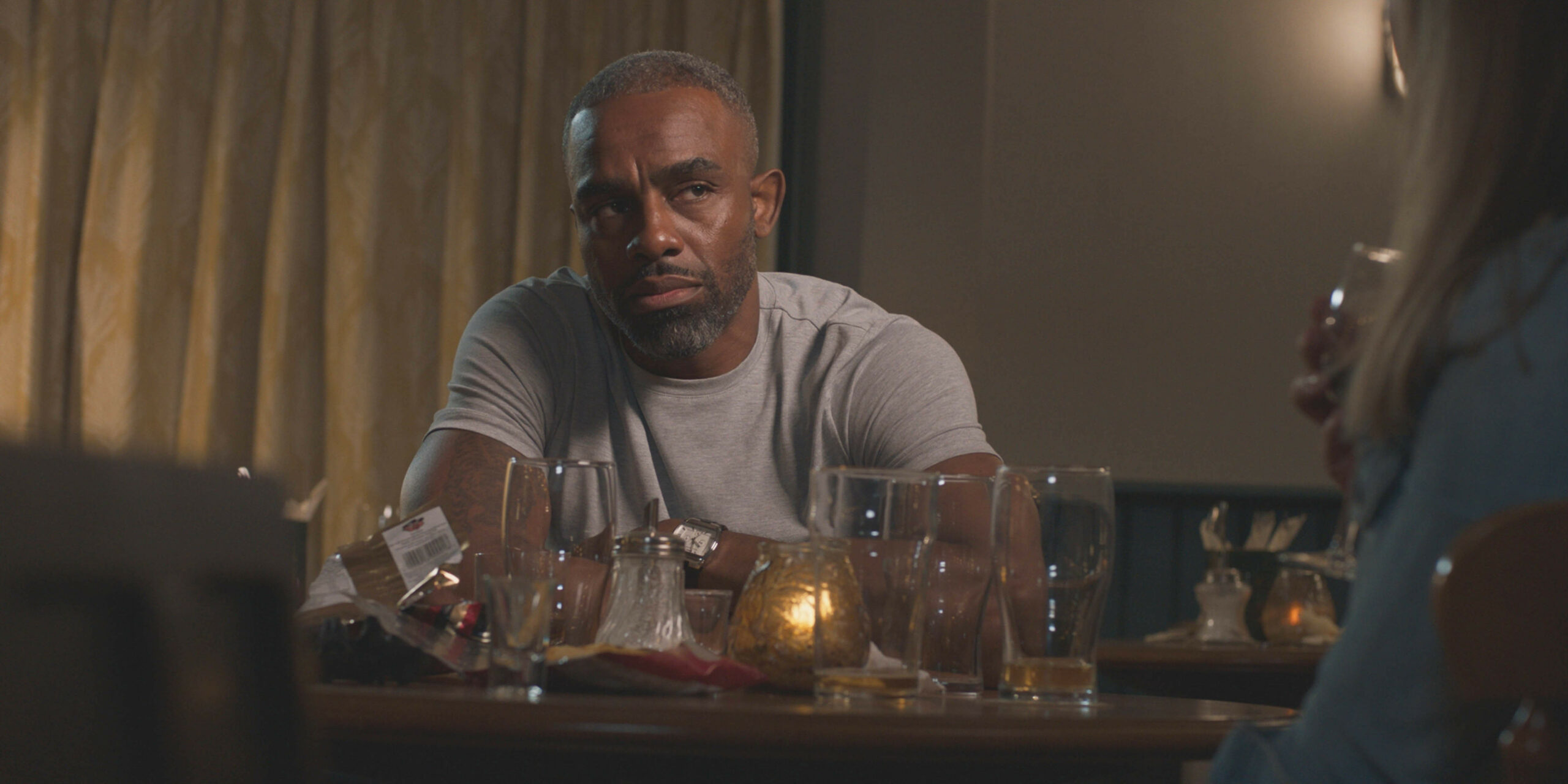 Jacob in a bar on Casualty, surrounded by empty glasses