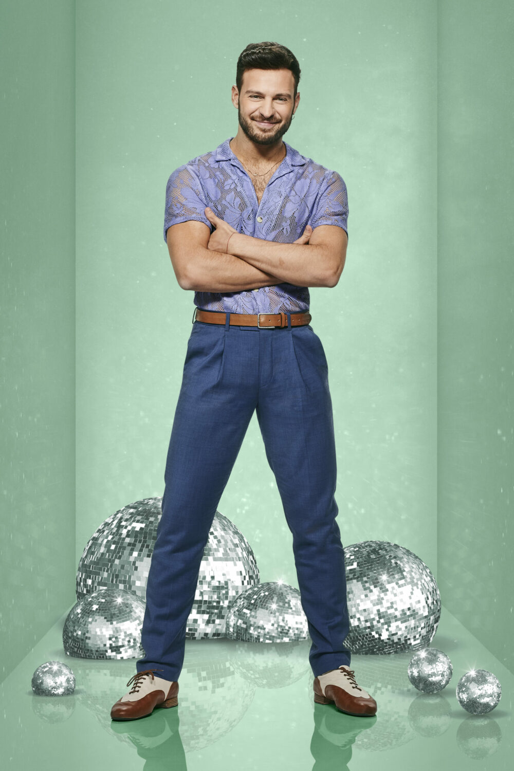 Vito Coppola poses in blue outfit with glitterballs in the background for Strictly promo shot