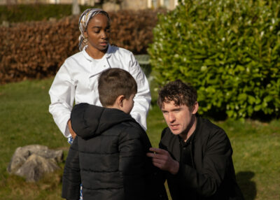 Alex kneels and talks to Clare's son, while Naomi watches on Emmerdale