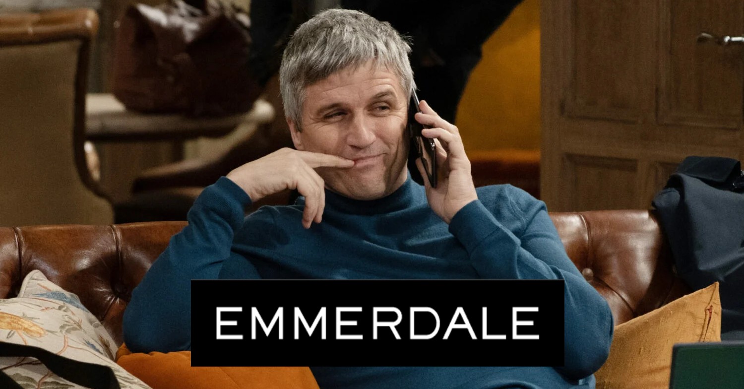 Emmerdale's Caleb on the phone smirking with the logo comp image