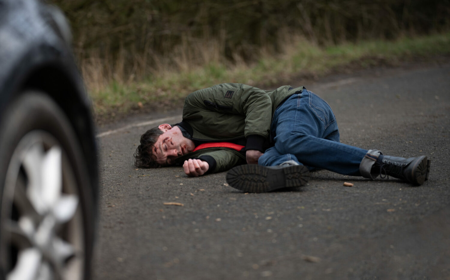 Emmerdale's Alex is lying on the road with blood on his face