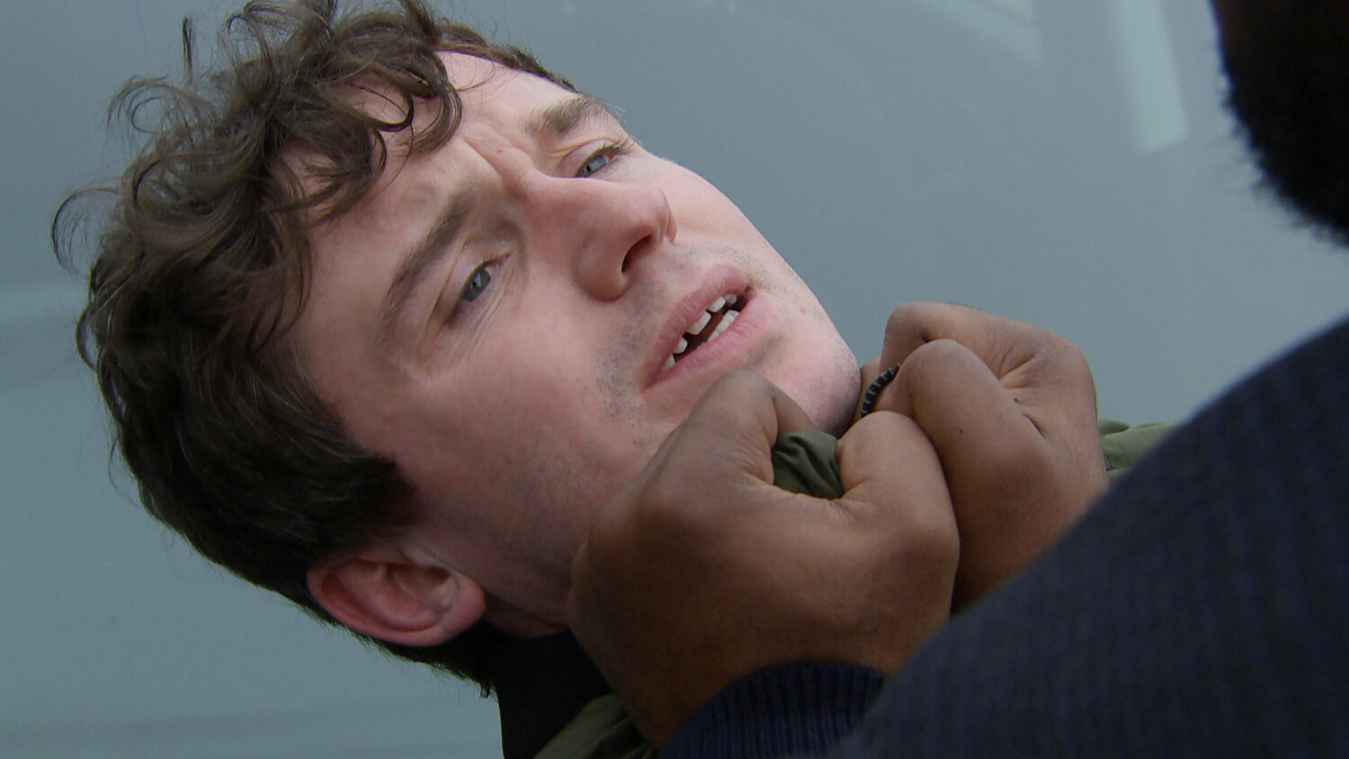 Alex squirms as Charles Anderson grabs him by collar and smashes him against a car