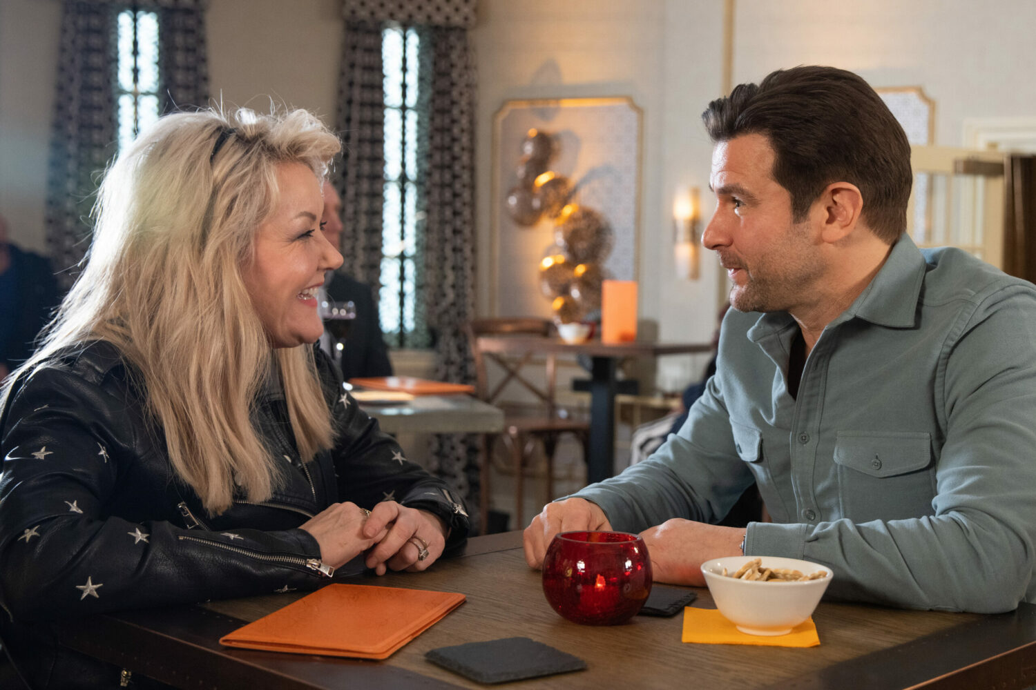 Beth and Marco smile as they share an intimate table at a hotel on Corrie