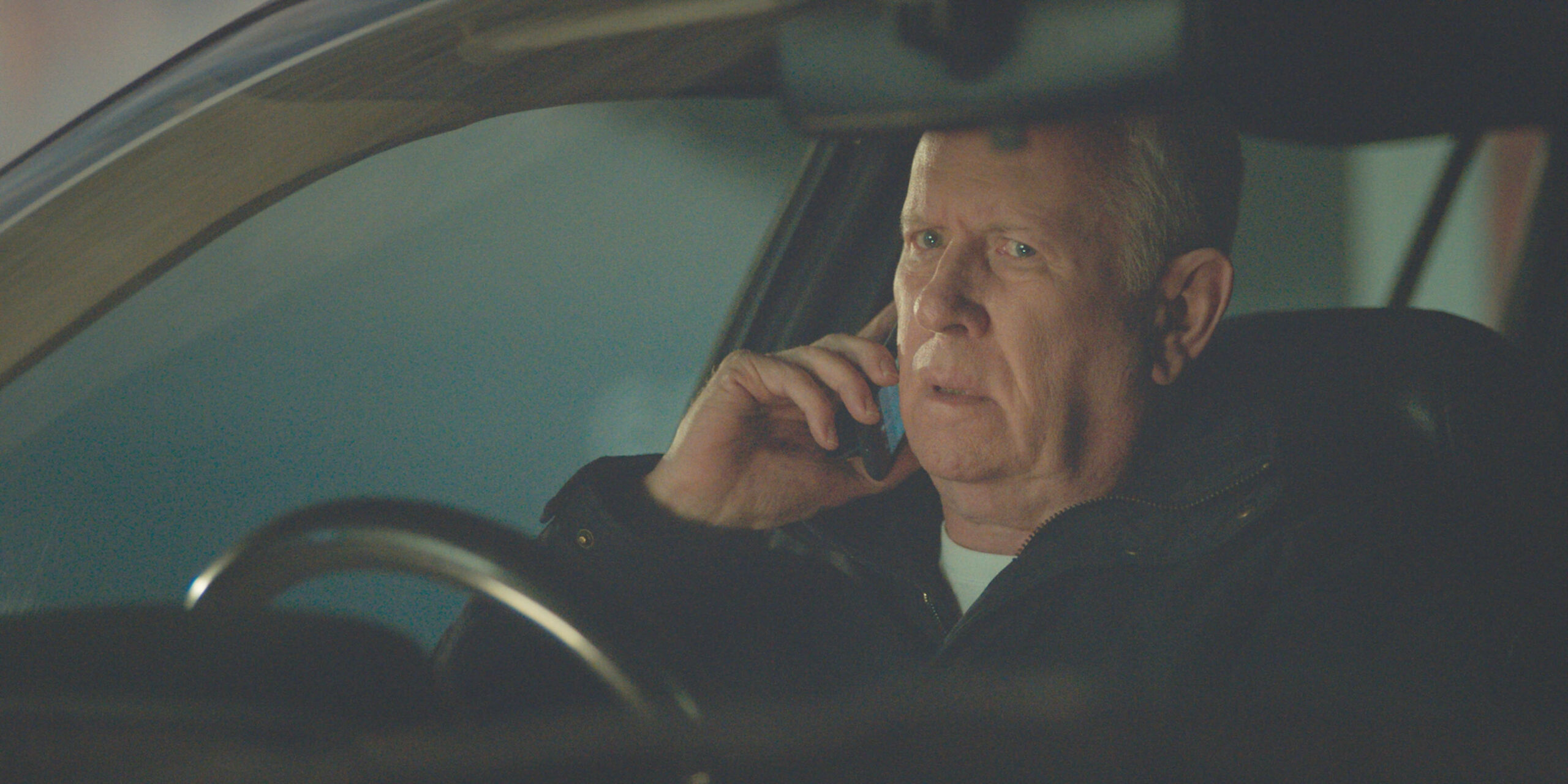 Casualty's Charlie looks worried whilst on the phone in the car